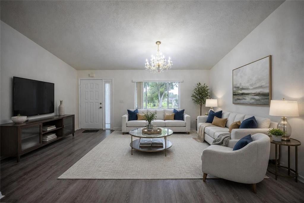 A living room with light gray flooring, a white sofa, a chandelier, and a television — 10452 SW 62ND TERRACE ROAD, OCALA, FL