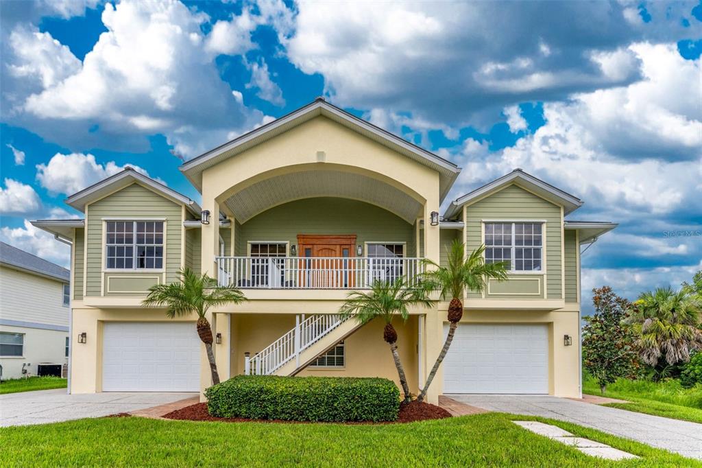 A two-story elevated house with a front balcony, two garage doors, and light green siding — 4219 SPIRE STREET, PORT CHARLOTTE, FL