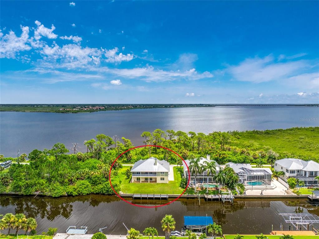 An aerial view shows a two-story house with a metal roof beside a canal — 4219 SPIRE STREET, PORT CHARLOTTE, FL