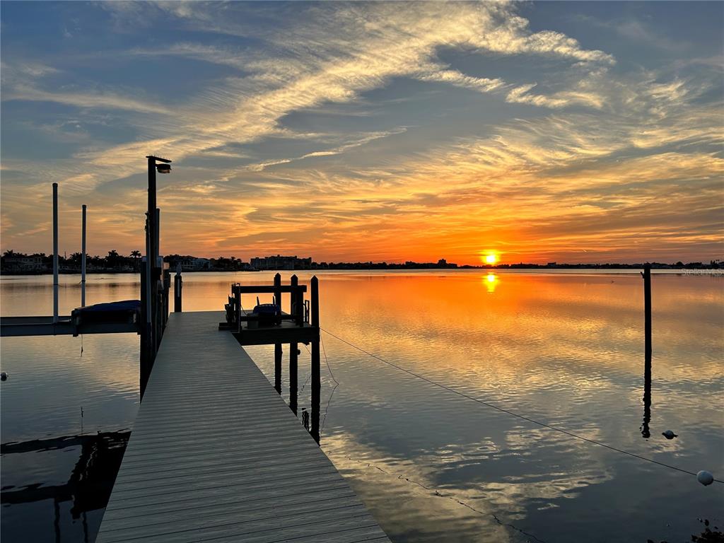 A wooden dock extends into a calm body of water during a vibrant sunset — 311 SUNSET DRIVE N, ST PETERSBURG, FL