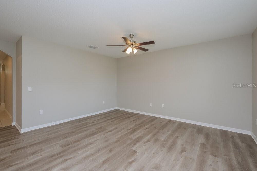 An empty room with light gray walls, a ceiling fan, and wood-look vinyl flooring — 14133 ARBOR PINES DRIVE, RIVERVIEW, FL
