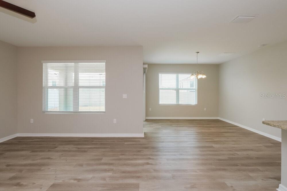 An open-concept living and dining area features light-colored walls and wood-look vinyl flooring — 14133 ARBOR PINES DRIVE, RIVERVIEW, FL