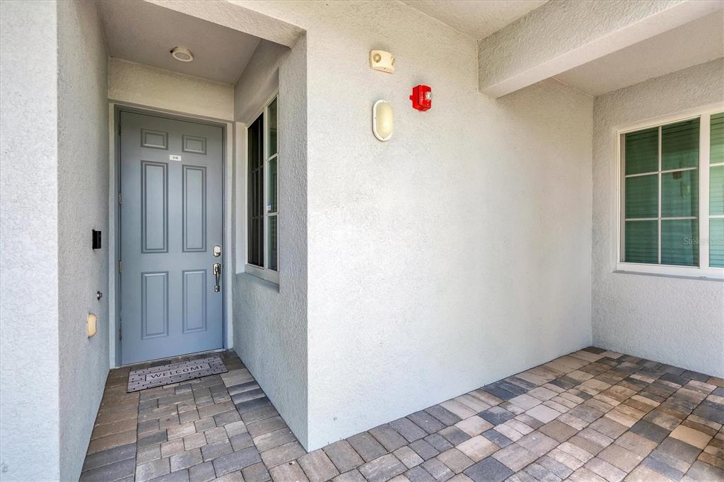 A gray front door opens onto a paved patio area with a window and light fixtures — 14071 HERITAGE LANDING BOULEVARD UNIT 316, PUNTA GORDA, FL