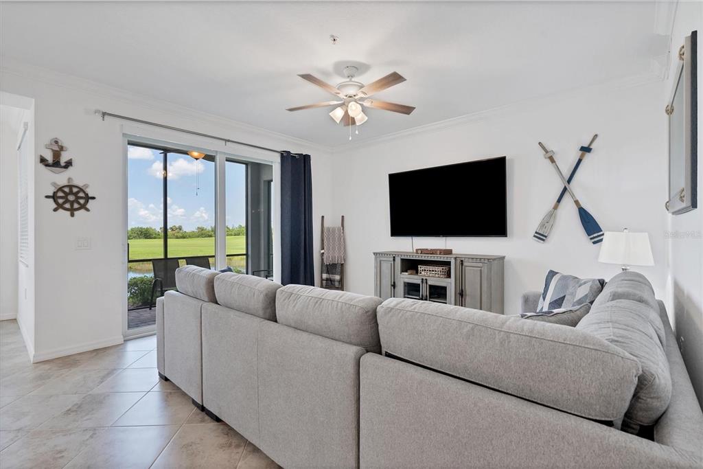 A living room features a grey sectional sofa, a television, and nautical wall decor — 14071 HERITAGE LANDING BOULEVARD UNIT 316, PUNTA GORDA, FL
