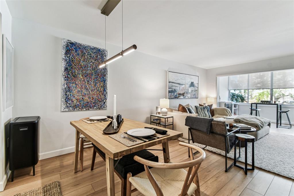 A living room features a sectional sofa, a large television, and a windowed dining area — 620 EDGEWATER DRIVE UNIT 204, DUNEDIN, FL
