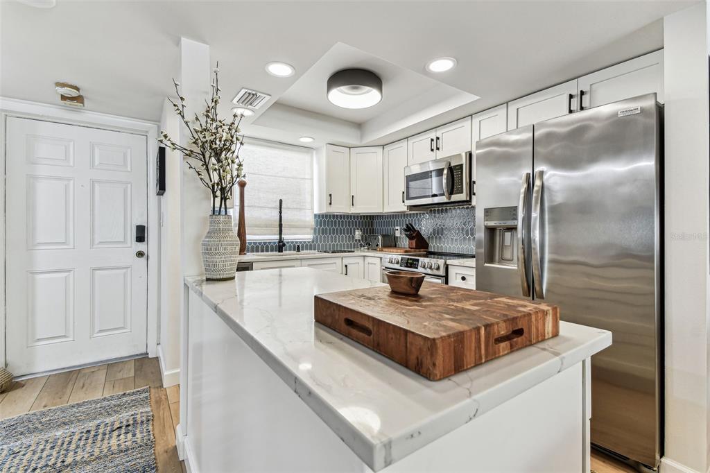 A dining area with a wooden table sits adjacent to a living room with neutral furniture — 620 EDGEWATER DRIVE UNIT 204, DUNEDIN, FL