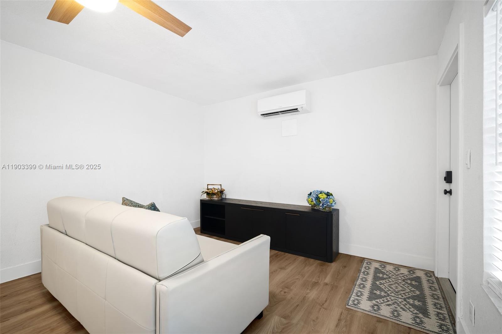 A living room features a white sofa, a black media console, and wood-look flooring — 9241 Collins Ave # 11, Surfside FL 33154, SURFSIDE, FL