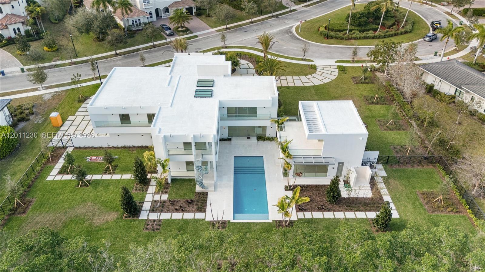 An aerial view shows a modern white house with a rectangular pool and landscaping — 3280 Lake Ridge Lane, Weston FL 33332, WESTON, FL