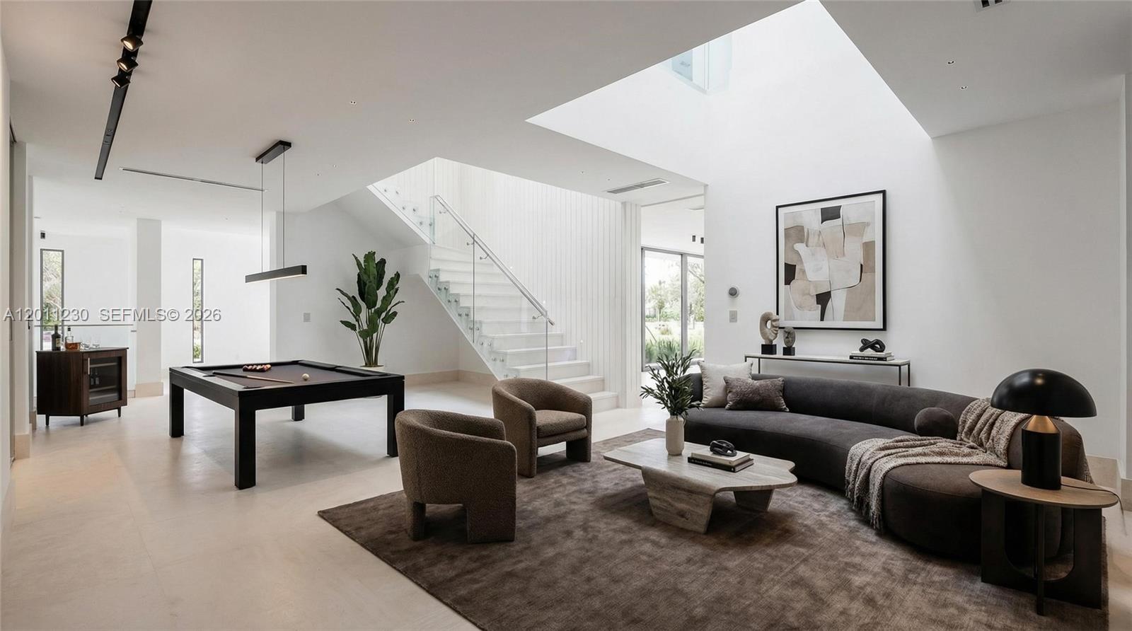 A modern living room features a pool table, a curved sofa, and a floating staircase — 3280 Lake Ridge Lane, Weston FL 33332, WESTON, FL