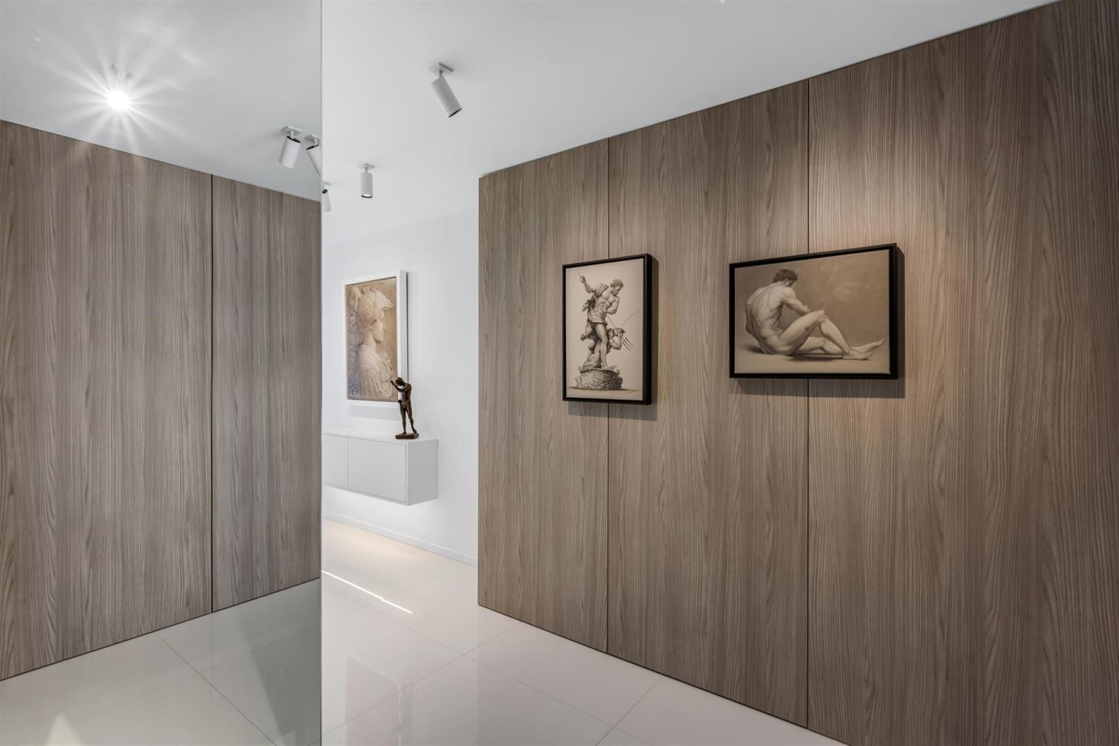 A hallway features wood-paneled walls, framed artwork, and a floating white cabinet on white floors — 3440 S Ocean Boulevard # 708s, Palm Beach FL 33480, PALM BEACH, FL