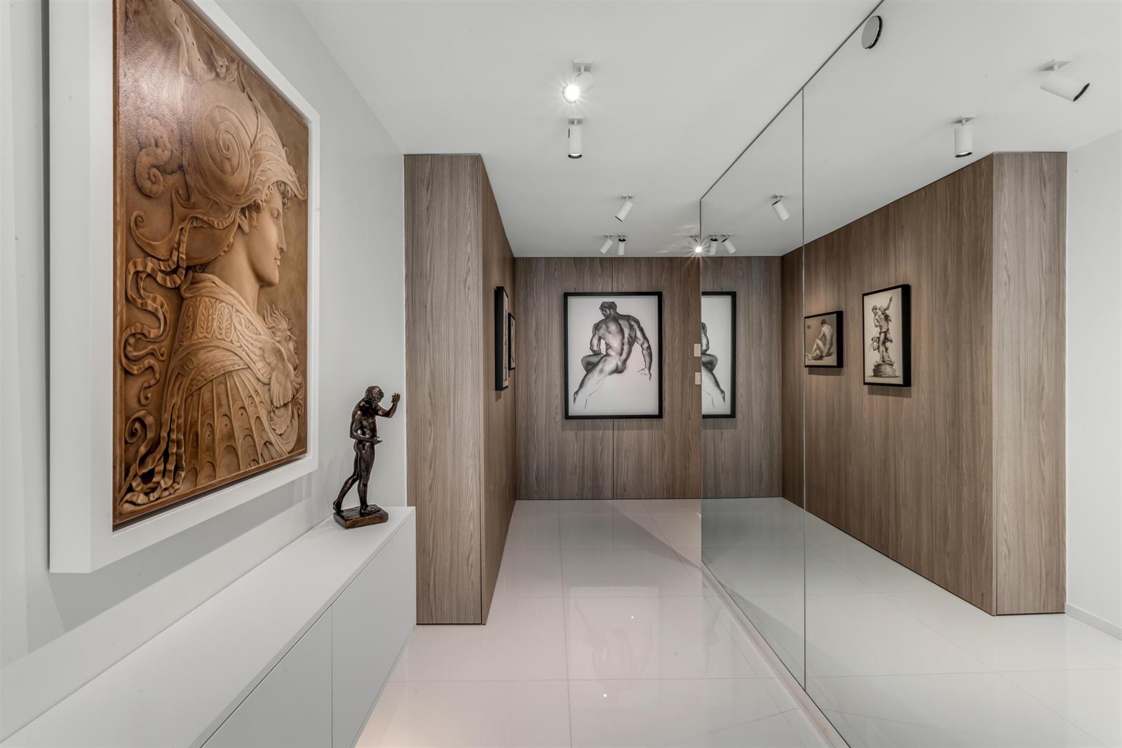 A hallway with wood-paneled walls, a large mirror, white tile floors, and framed artwork — 3440 S Ocean Boulevard # 708s, Palm Beach FL 33480, PALM BEACH, FL