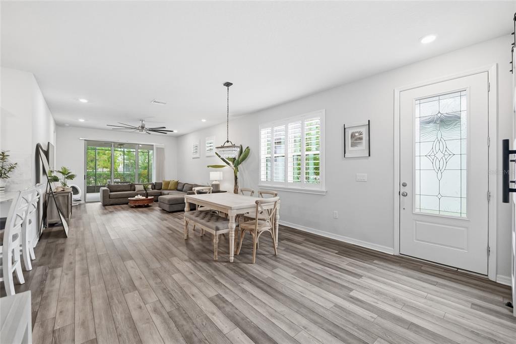 An open-concept living and dining area features light wood-look flooring and a white front door — 6308 MOORING LINE CIRCLE, APOLLO BEACH, FL
