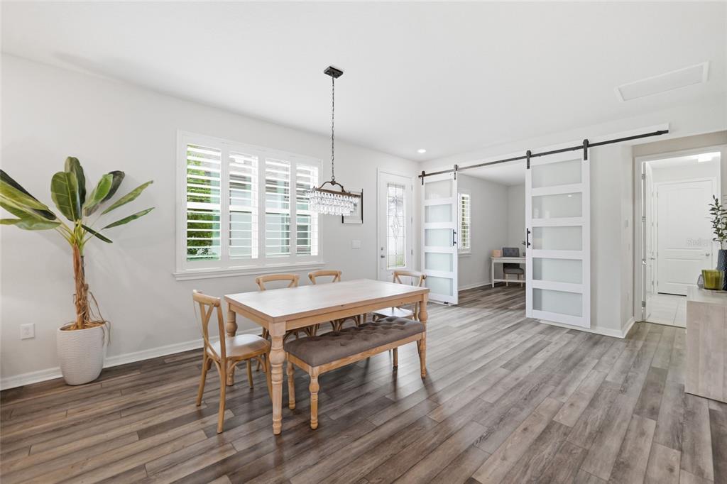 A dining room features wood-look flooring, a wooden table with bench seating, and sliding glass doors — 6308 MOORING LINE CIRCLE, APOLLO BEACH, FL
