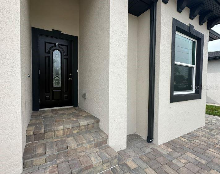 A black front door with a decorative window sits above stone steps at an entrance — 55 BOUNDARY BOULEVARD UNIT A, ROTONDA WEST, FL