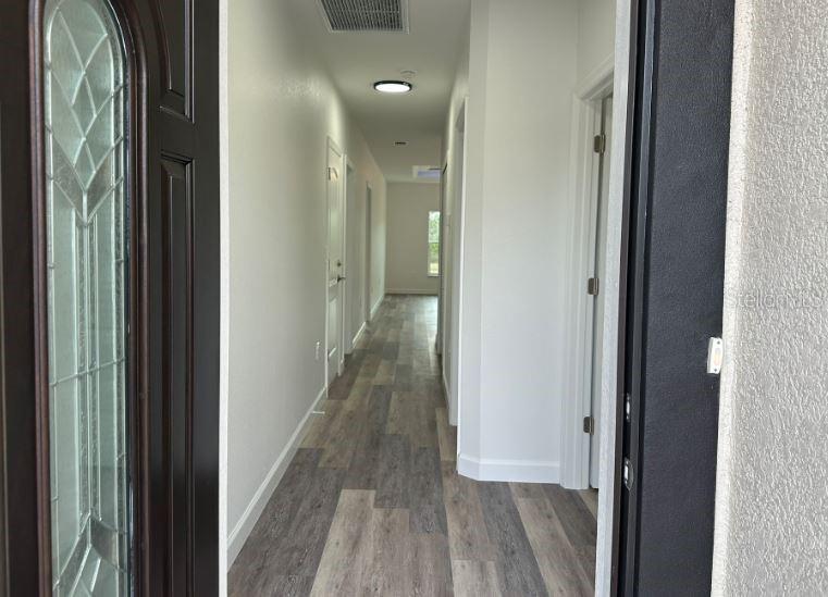 A view from a front doorway looking down a hallway with wood-look flooring — 55 BOUNDARY BOULEVARD UNIT A, ROTONDA WEST, FL