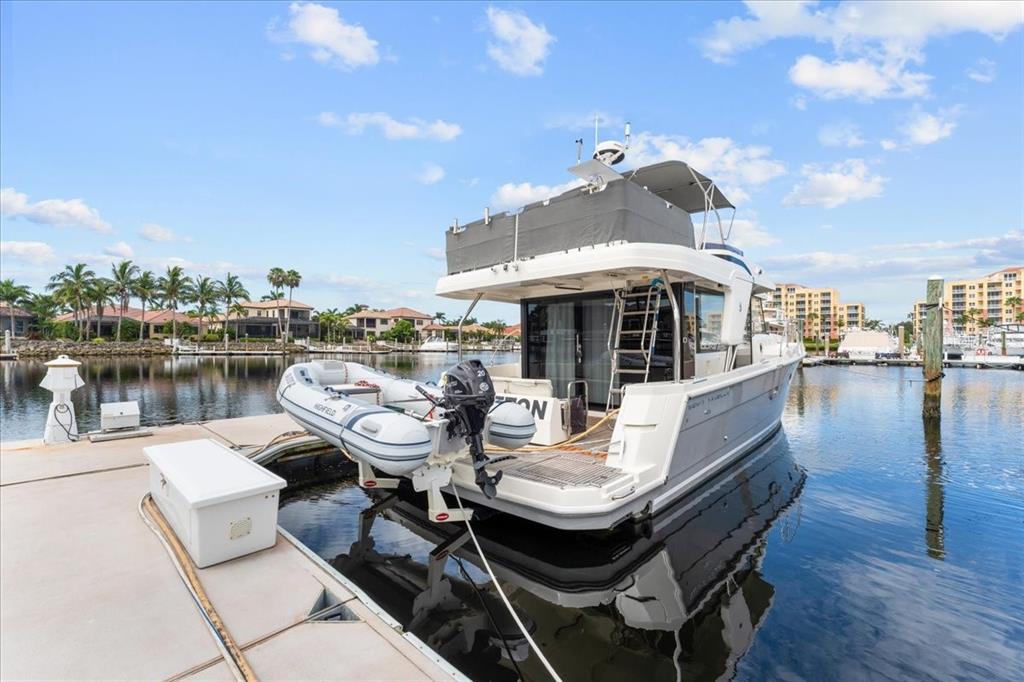 A white motor yacht with an attached dinghy is docked at a residential waterfront pier — 102 RIVIERA DUNES WAY UNIT S-36, PALMETTO, FL