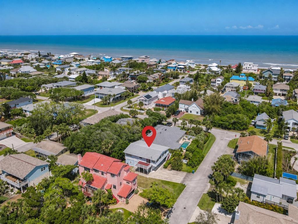 An aerial view shows a coastal neighborhood with a red-roofed house and a marked property — 824 GARFISH AVENUE, NEW SMYRNA BEACH, FL