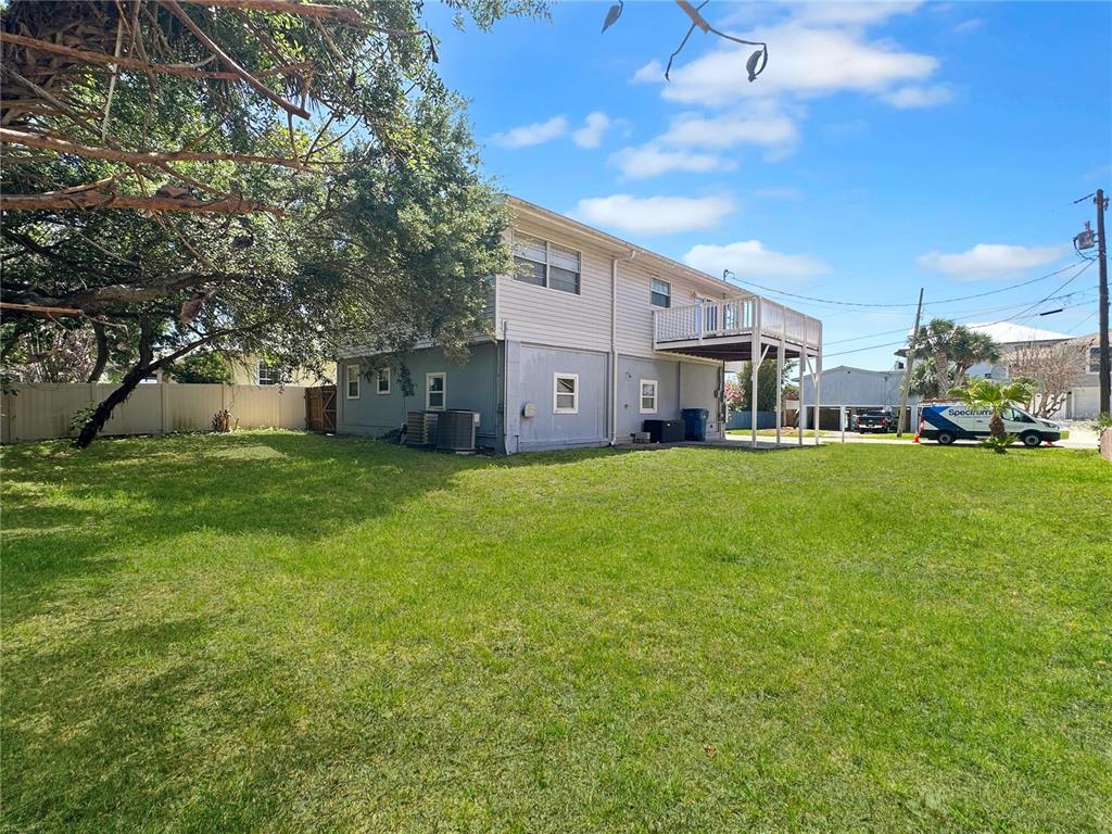 A two-story house with light siding and a raised deck stands in a grassy yard — 824 GARFISH AVENUE, NEW SMYRNA BEACH, FL