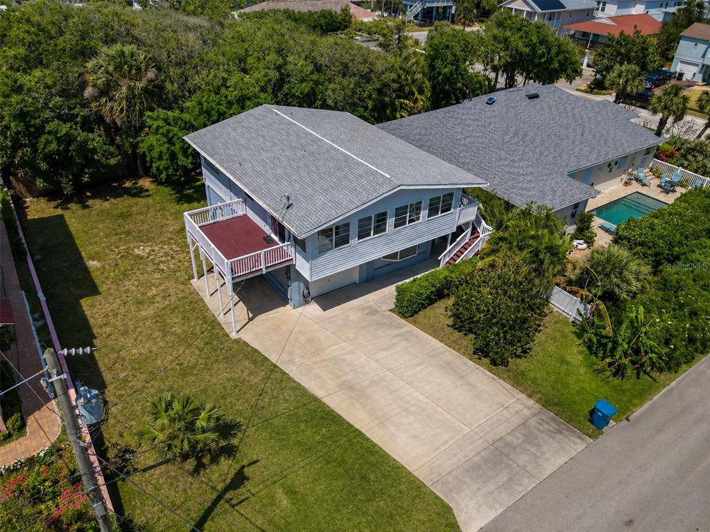 An elevated house with a red deck, gray roof, and concrete driveway in a neighborhood — 824 GARFISH AVENUE, NEW SMYRNA BEACH, FL