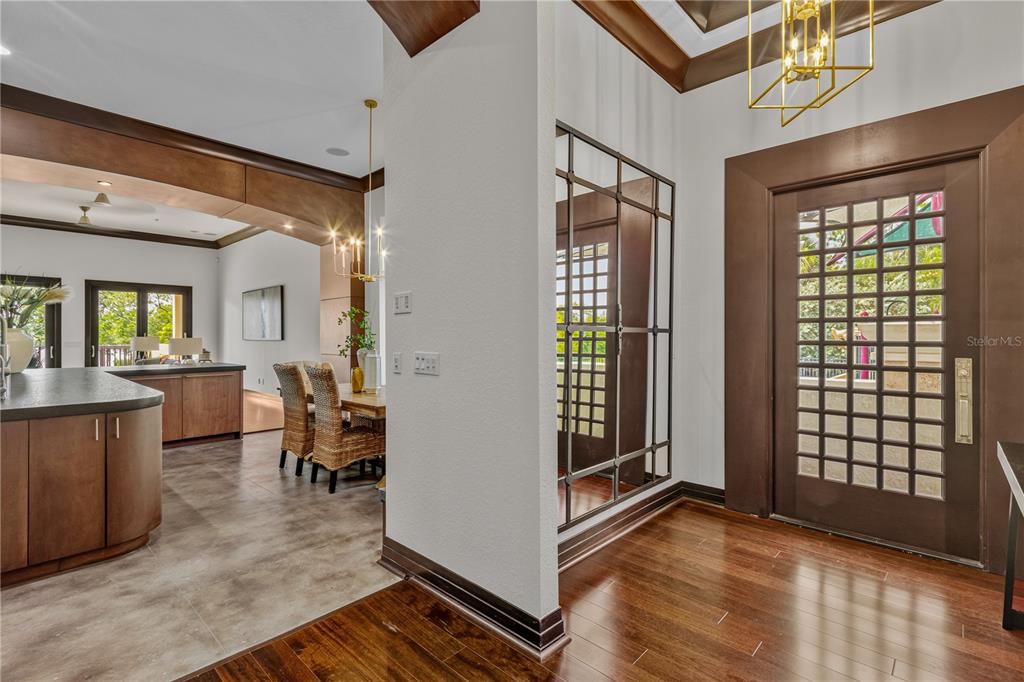 An entryway with hardwood floors, a grid-paneled mirror, and a view into a dining area — 1008 PASEO DEL RIO NE, ST PETERSBURG, FL