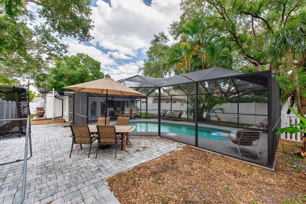 A backyard features a screened-in swimming pool, a paved patio, and outdoor dining furniture — 1715 S HUBERT AVENUE, TAMPA, FL