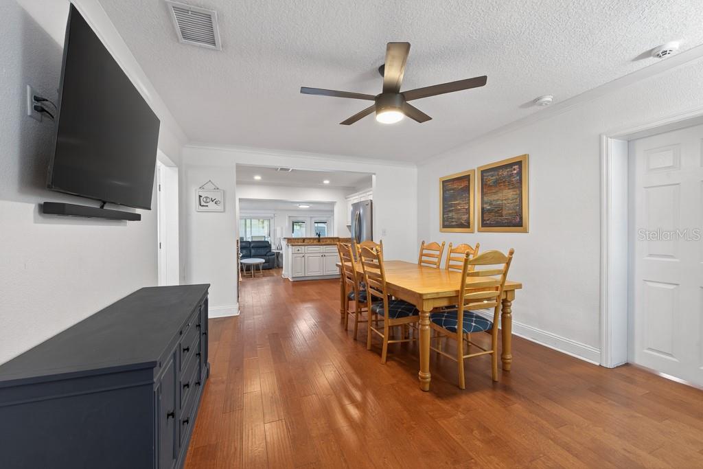 A dining area with a wooden table and chairs leads into a kitchen with white cabinets — 1715 S HUBERT AVENUE, TAMPA, FL