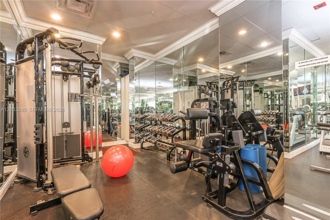 A gym room features mirrored walls, various weight machines, a red exercise ball, and dumbbells — 2030 S Ocean Dr # 1826, Hallandale Beach FL 33009, HALLANDALE BEACH, FL