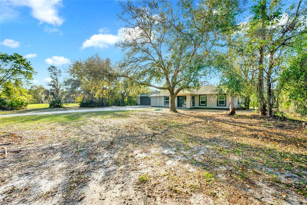 A single-story house with a garage sits on a large, tree-filled lot — 1811 BUTCH CASSIDY TRAIL, WIMAUMA, FL