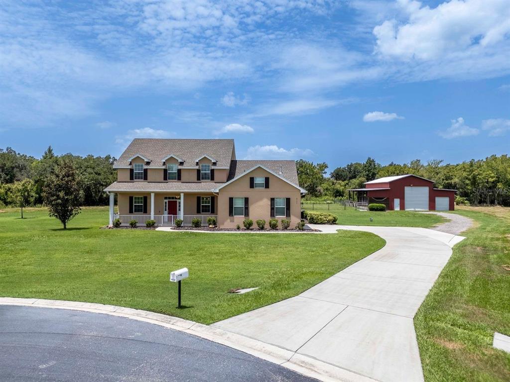 A two-story house with a front porch, a concrete driveway, and a detached red barn — 8703 ALAFIA HILLS DRIVE, PLANT CITY, FL