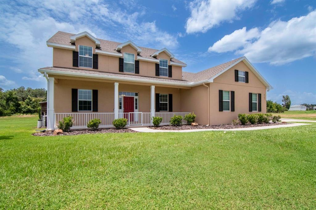 A two-story house with a tan exterior, a front porch, and a large grassy lawn — 8703 ALAFIA HILLS DRIVE, PLANT CITY, FL