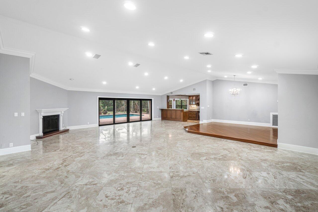 A spacious living room features light marble flooring, a fireplace, and a raised wood platform — 2150 NW 23rd Way, Boca Raton FL 33431, BOCA RATON, FL