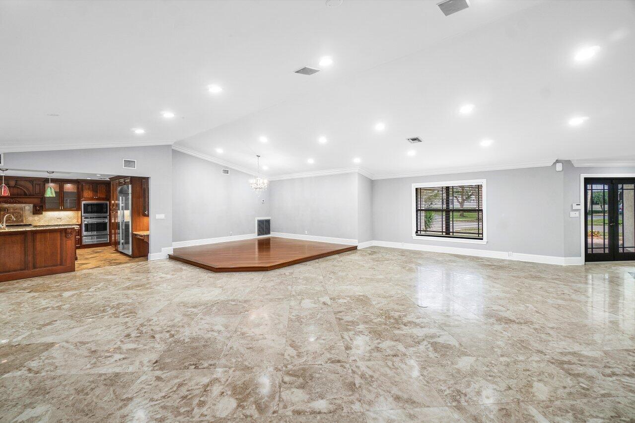 A spacious room features light marble flooring, a raised wood platform, and an adjacent kitchen — 2150 NW 23rd Way, Boca Raton FL 33431, BOCA RATON, FL