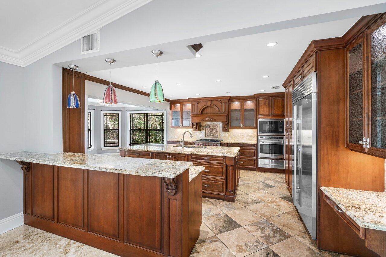 A spacious kitchen features wood cabinetry, granite countertops, a central island, and tile flooring — 2150 NW 23rd Way, Boca Raton FL 33431, BOCA RATON, FL