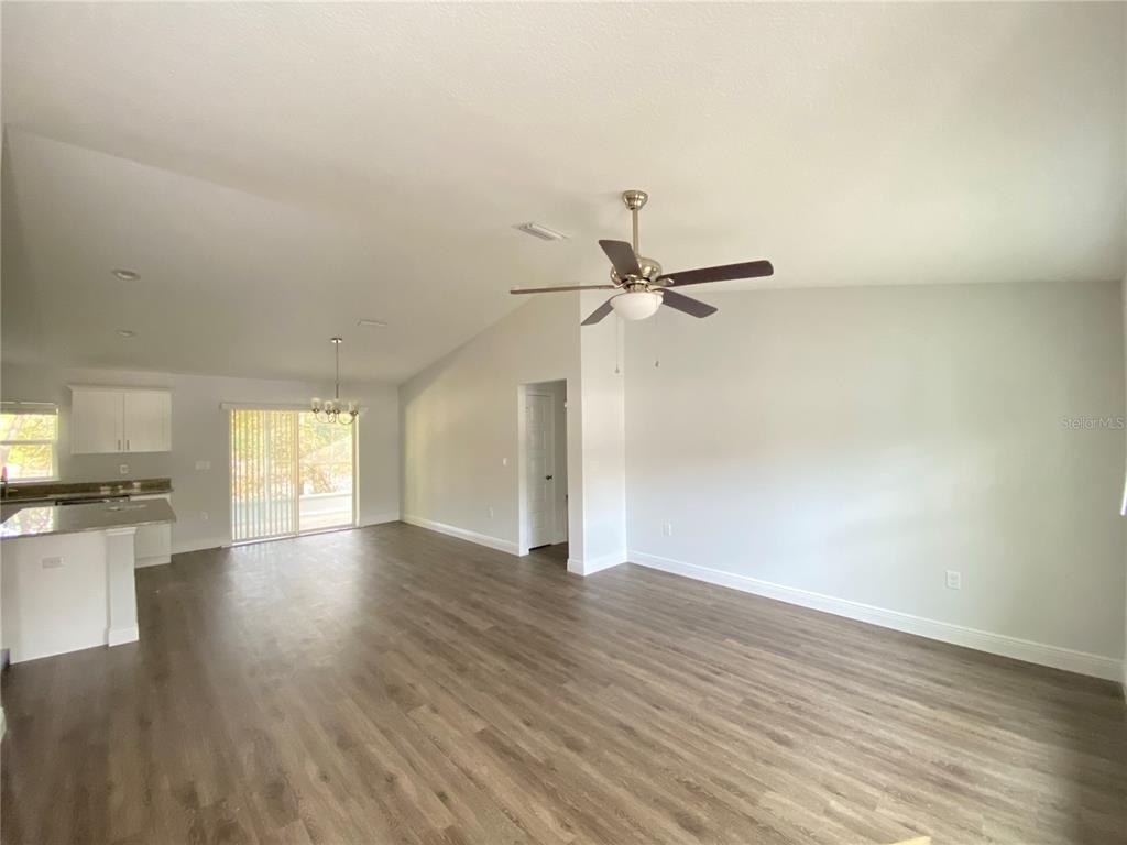 An open-concept living area features vaulted ceilings, a ceiling fan, and wood-look flooring — 9205 N ELKCAMP BOULEVARD, CITRUS SPRINGS, FL