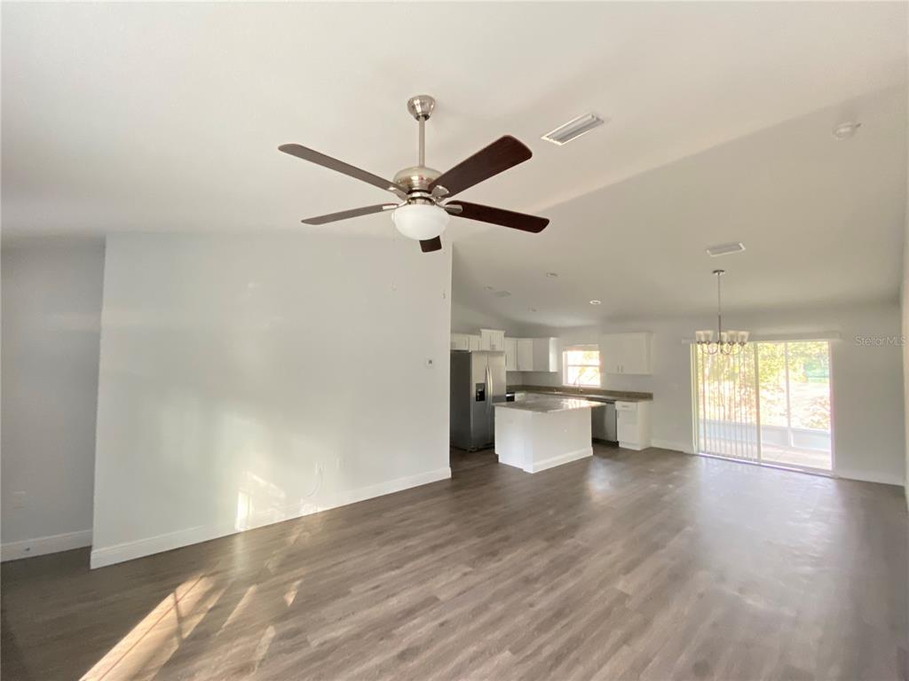 An open-concept living area features a ceiling fan, wood-look flooring, and a kitchen with island — 9205 N ELKCAMP BOULEVARD, CITRUS SPRINGS, FL