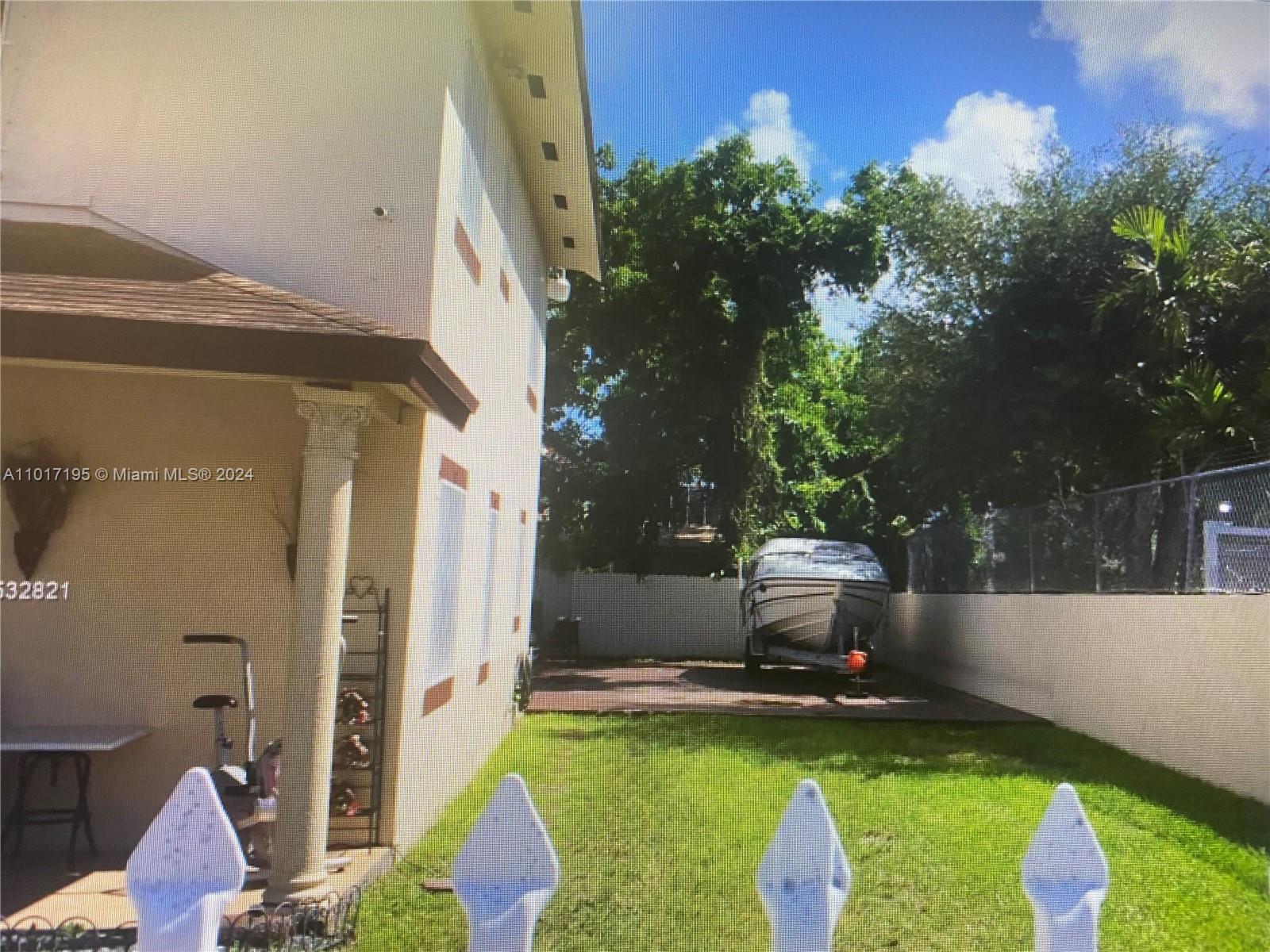 A side yard features a grassy lawn, a paved area with a boat, and a fence — 160 NW 27th St, Miami FL 33127, MIAMI, FL