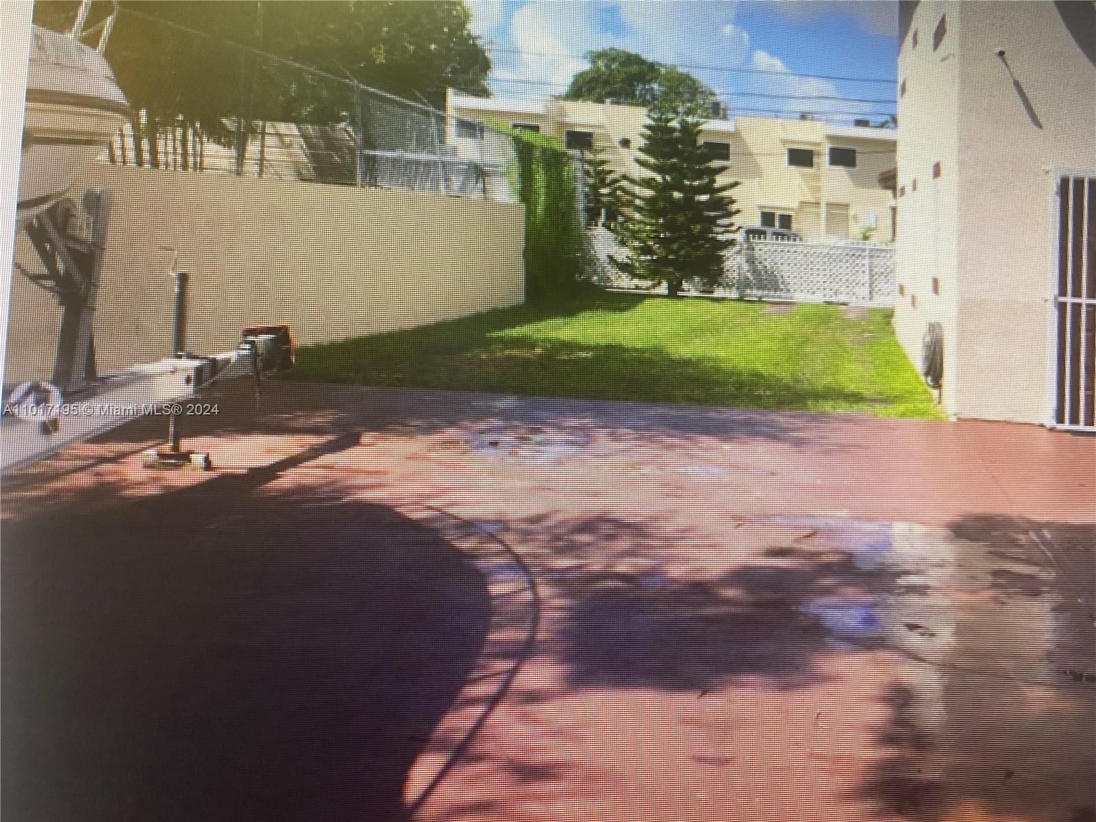 A paved patio area sits adjacent to a small grassy yard and a residential building — 160 NW 27th St, Miami FL 33127, MIAMI, FL