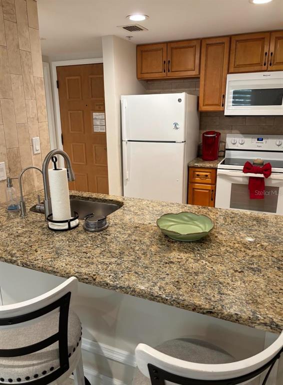 A kitchen features granite countertops, wood cabinets, a white refrigerator, and a stainless steel stove — 36750 US HIGHWAY 19 N UNIT 9-123, PALM HARBOR, FL