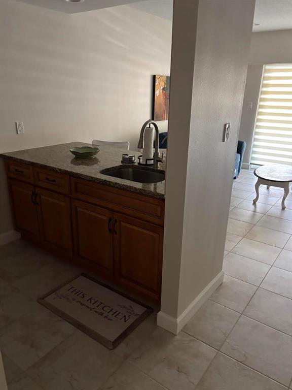 A kitchen island with a sink and granite countertop sits in a tiled room — 36750 US HIGHWAY 19 N UNIT 9-123, PALM HARBOR, FL