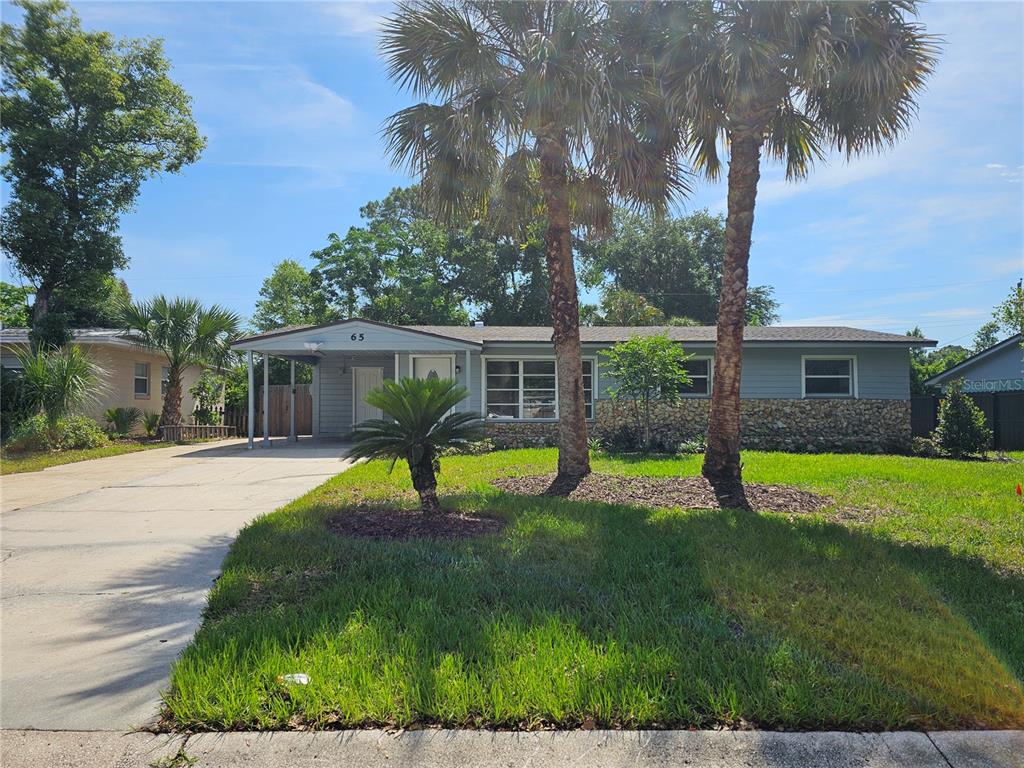 A single-story house with a stone facade, a carport, and two palm trees in front — 65 S DEVON AVENUE, WINTER SPRINGS, FL