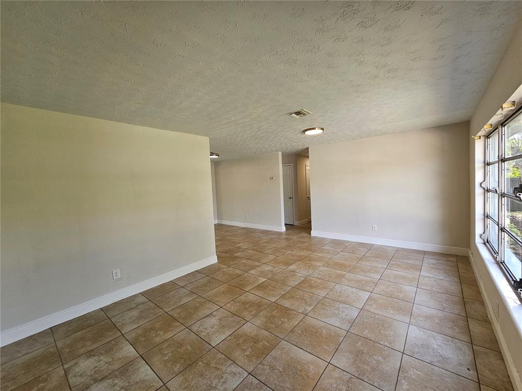 An empty room with tan tile flooring, beige walls, and a textured ceiling — 65 S DEVON AVENUE, WINTER SPRINGS, FL