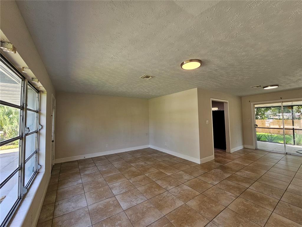 An empty room features tan tile flooring, light-colored walls, and sliding glass doors — 65 S DEVON AVENUE, WINTER SPRINGS, FL