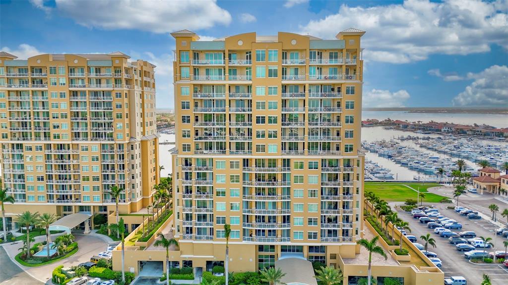 An aerial view of two tall, tan residential buildings next to a marina with boats — 130 RIVIERA DUNES WAY UNIT 506, PALMETTO, FL