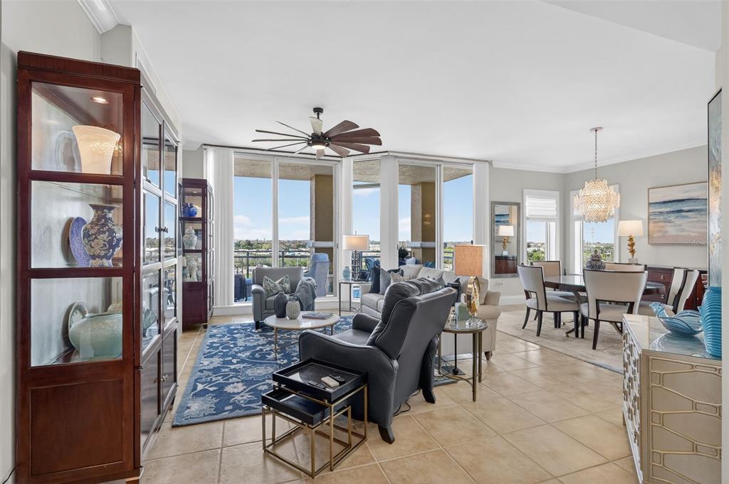 A bright open-concept living and dining area features tile floors, a ceiling fan, and balcony access — 130 RIVIERA DUNES WAY UNIT 506, PALMETTO, FL