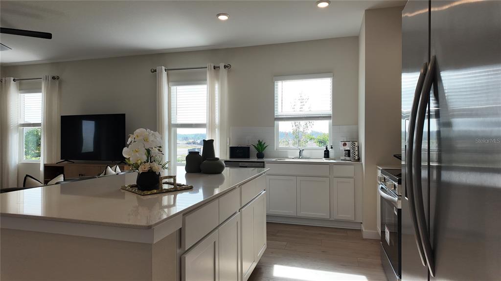A kitchen with white cabinets, a large island, and stainless steel appliances — 5160 NATALIA DRIVE, ST CLOUD, FL