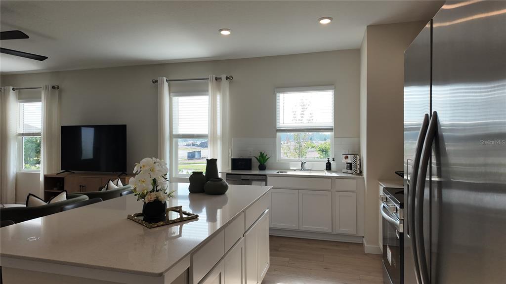 A modern kitchen with a large island, white cabinets, and stainless steel appliances — 5160 NATALIA DRIVE, ST CLOUD, FL
