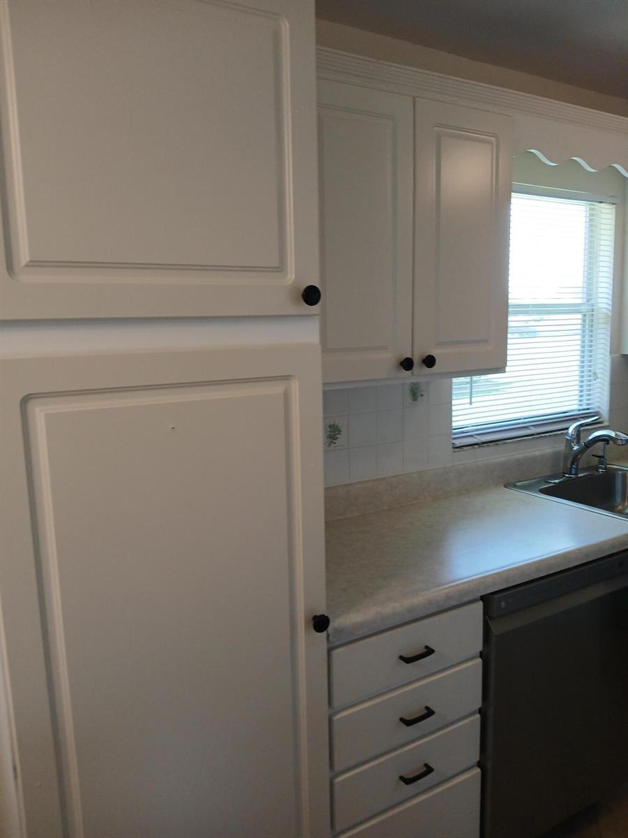 A kitchen features white cabinets, a light-colored countertop, a stainless steel sink, and drawers — 92 Seville Drive, Delray Beach FL 33446, DELRAY BEACH, FL