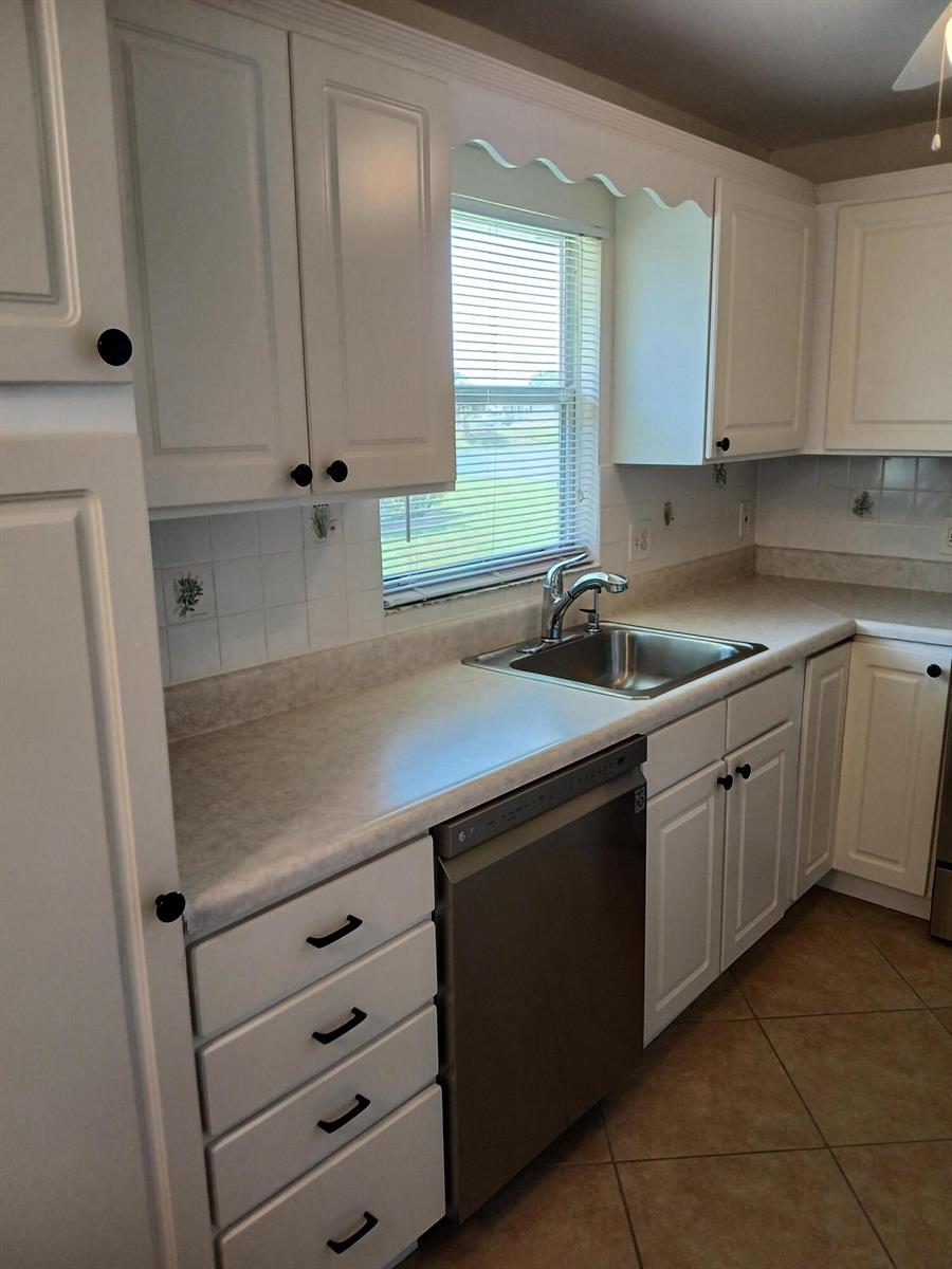 A kitchen features white cabinets, a stainless steel dishwasher, and a window above the sink — 92 Seville Drive, Delray Beach FL 33446, DELRAY BEACH, FL