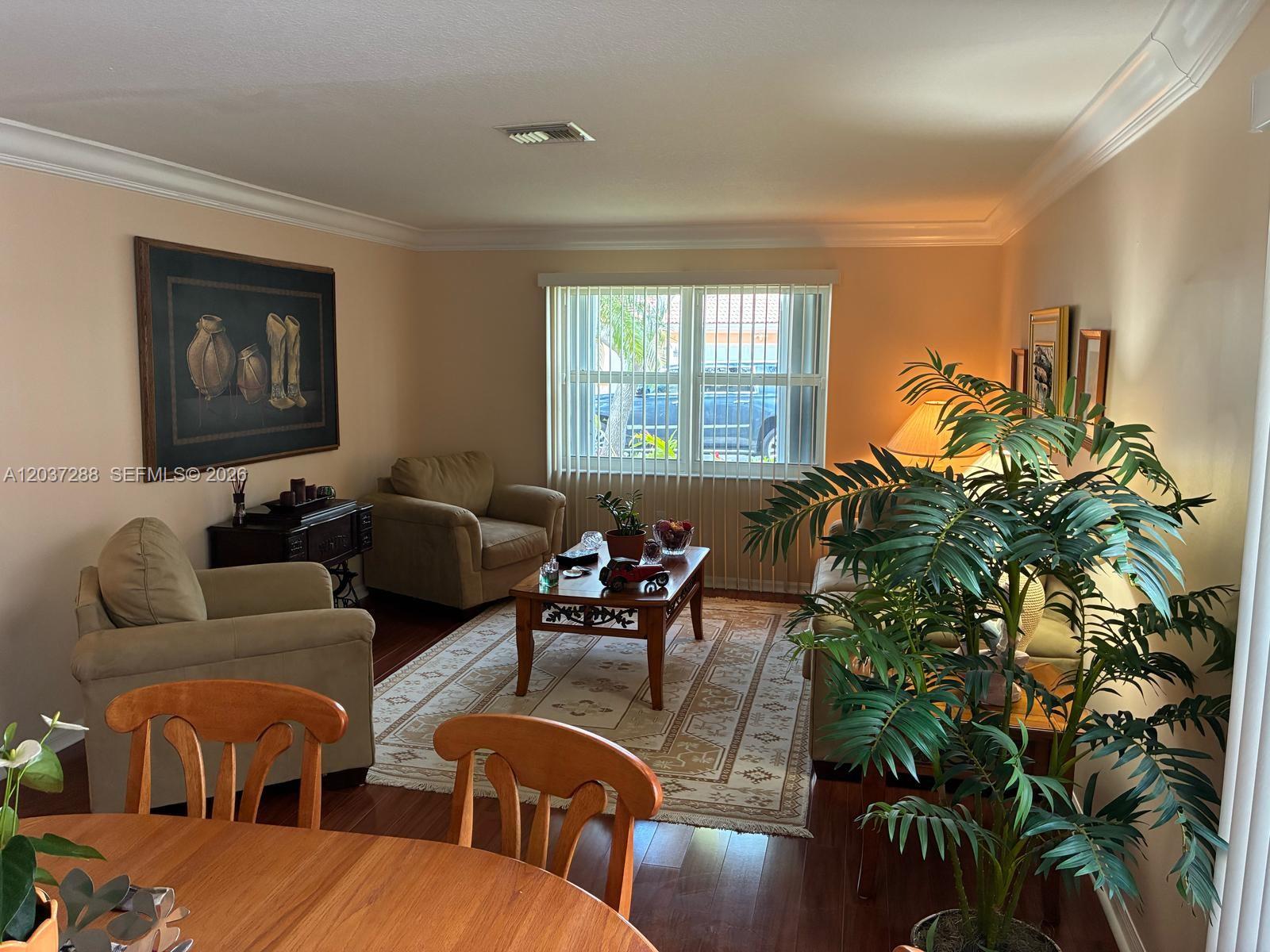A living room features beige walls, hardwood floors, a patterned area rug, and a large plant — 1412 NW 129th Terrace, Sunrise FL 33323, SUNRISE, FL