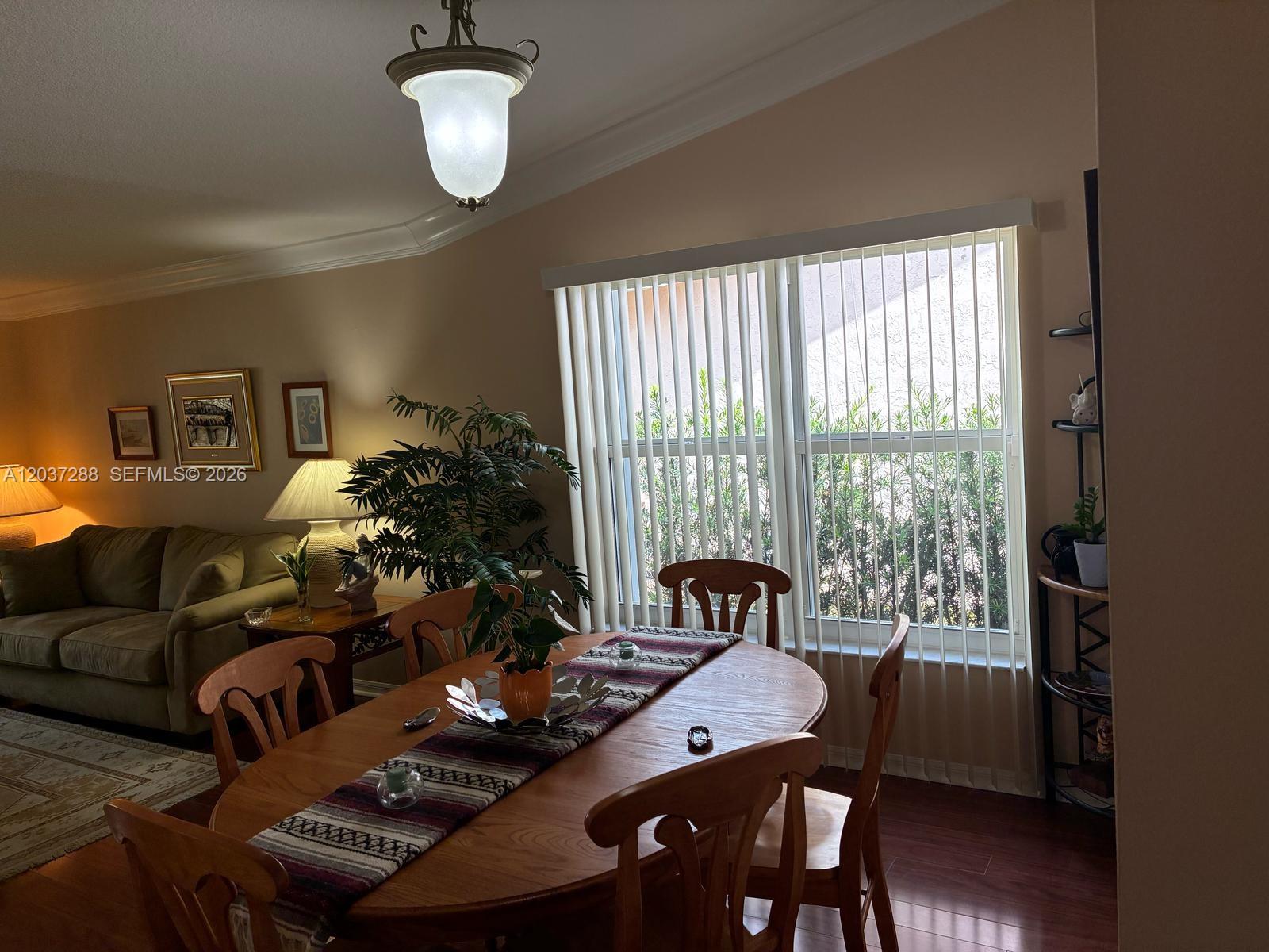 A dining area with a wooden table, chairs, and vertical blinds covering a large window — 1412 NW 129th Terrace, Sunrise FL 33323, SUNRISE, FL